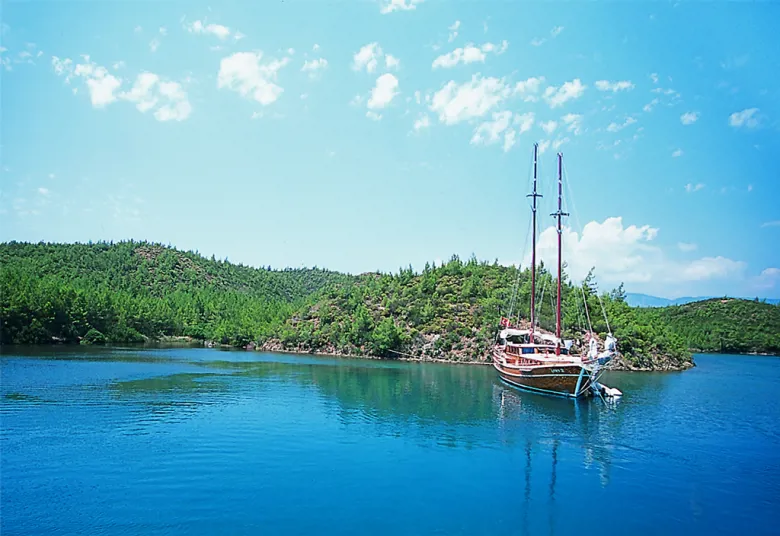Korunaklı mavi bir koyda demirlemiş geleneksel gulet